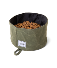 A green waxed canvas waterproof collapsible dog bowl is filled with dog food